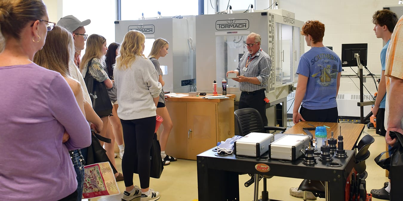Instructor Al Rossner demonstrates equipment in Jackson College's STEAM Factory while guests looks on.