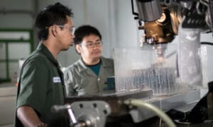 2 students working on a manufacturing machine.