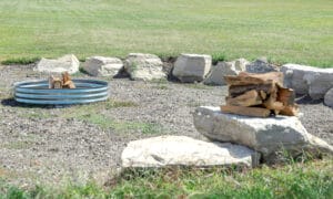 Bonfire ring in a gravel pit with rocks surrounding it for chairs.