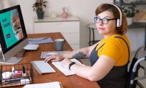 woman in wheelchair sitting at computer desk