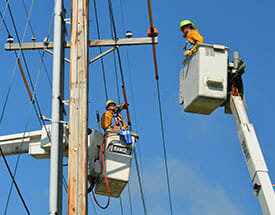 line workers in buckets at utility pole