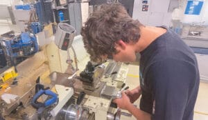 male student working over manufacturing machinery