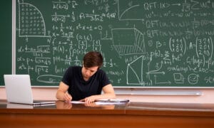 male student studying math in front of chalkboard