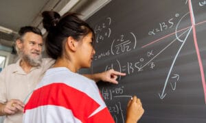 Woman and man writing math problems on a chalkboard