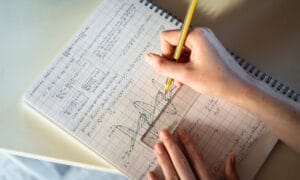 A person writing in a notebook math problems