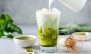 Milk pouring into a glass of matcha
