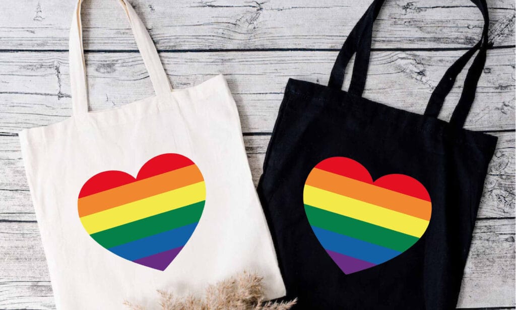 Tote bags with pride rainbow hearts on them.