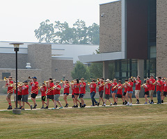summer band marching across campus
