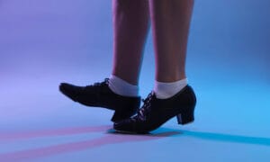 A close up of 2 feet tap dancing.