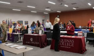 Tables set up of different colleges and JC resources talking to students.