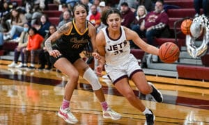 two female basketball players running down the court.